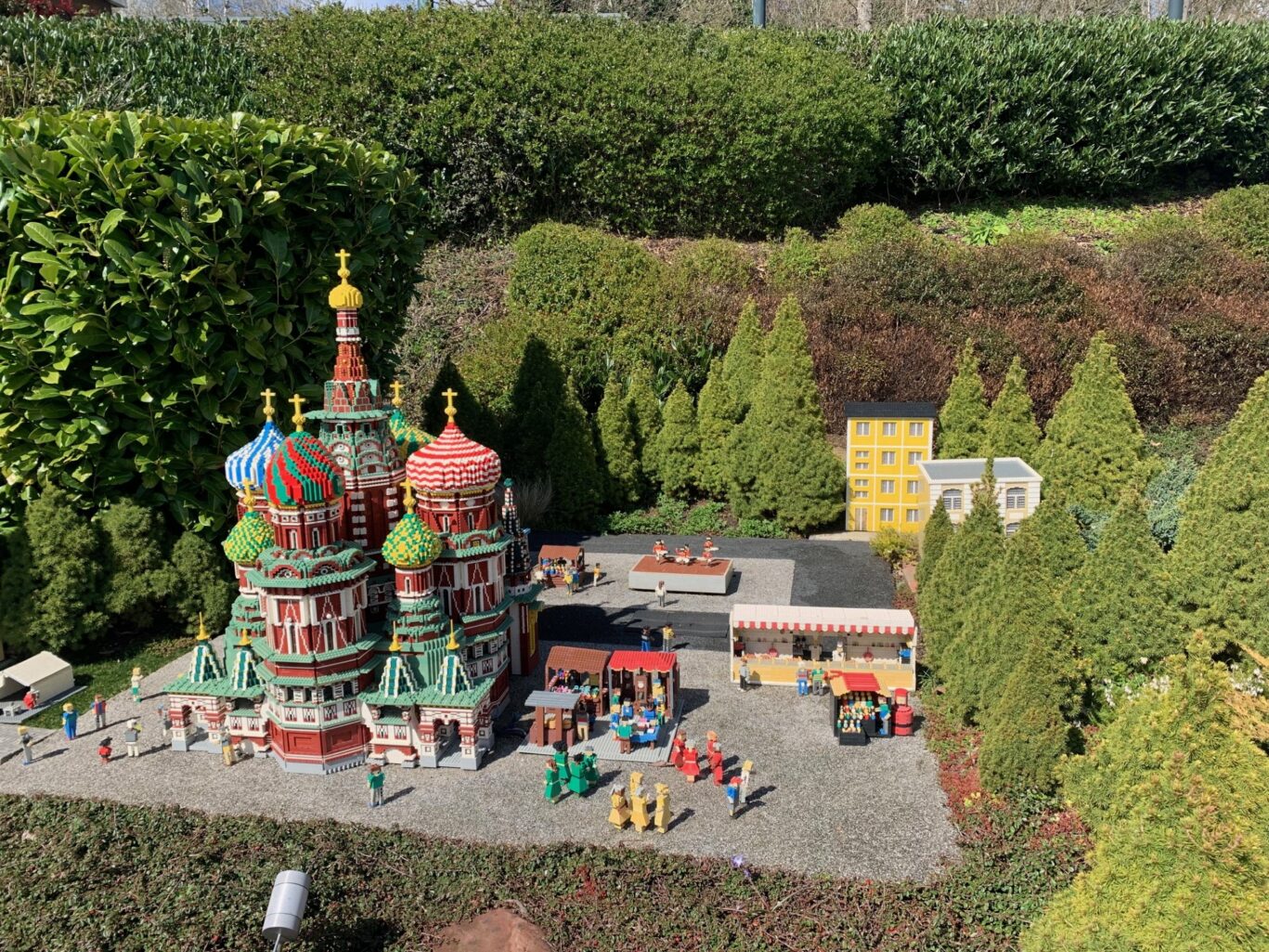 A detailed miniature LEGO replica of St. Basil's Cathedral with vibrant colored domes, displayed alongside mini figures and market stalls in Miniland at LEGOLAND Windsor.