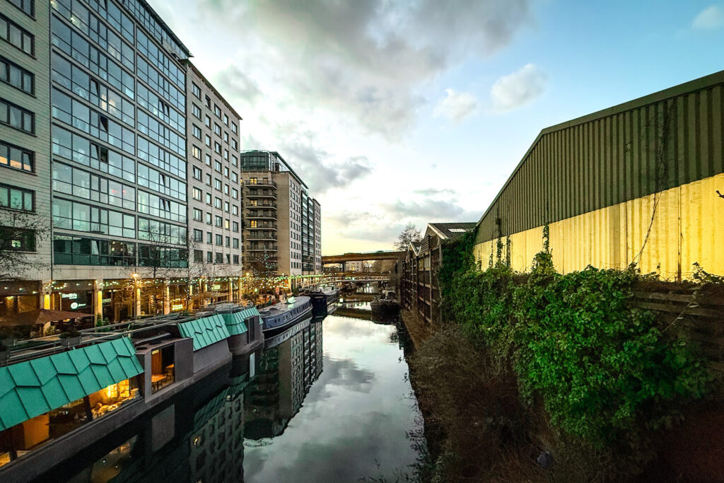 London Paddington Basin featuring an autumn sunset over the Grand Union canal, with canal boats on the side lit by fairy lights.